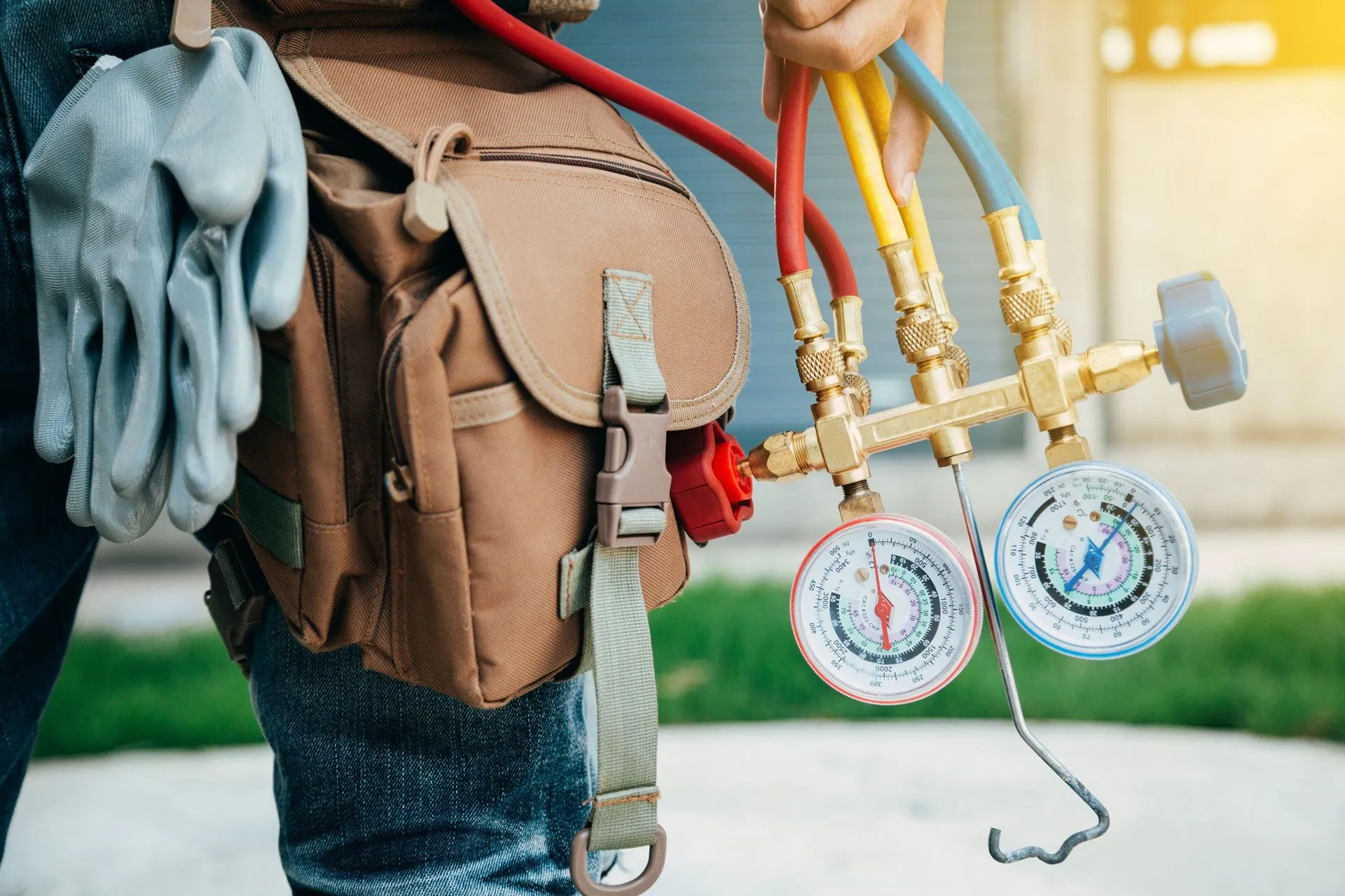 A man is holding a pair of gauges and a hose. AC repair service in Gresham OR