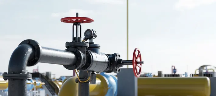 A close up of a gas pipe with a red valve on it.