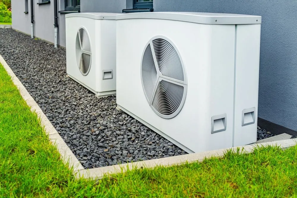 Two air conditioners are sitting next to each other on the side of a building. Heat pump service in Gresham OR