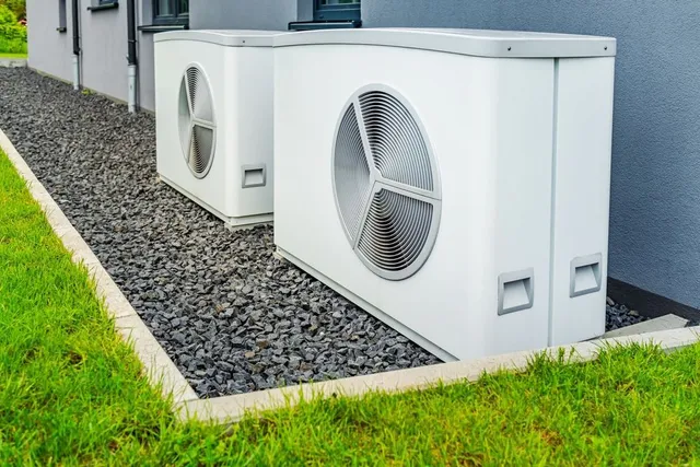 Two air conditioners are sitting next to each other on the side of a building. Heat pump service in Gresham OR
